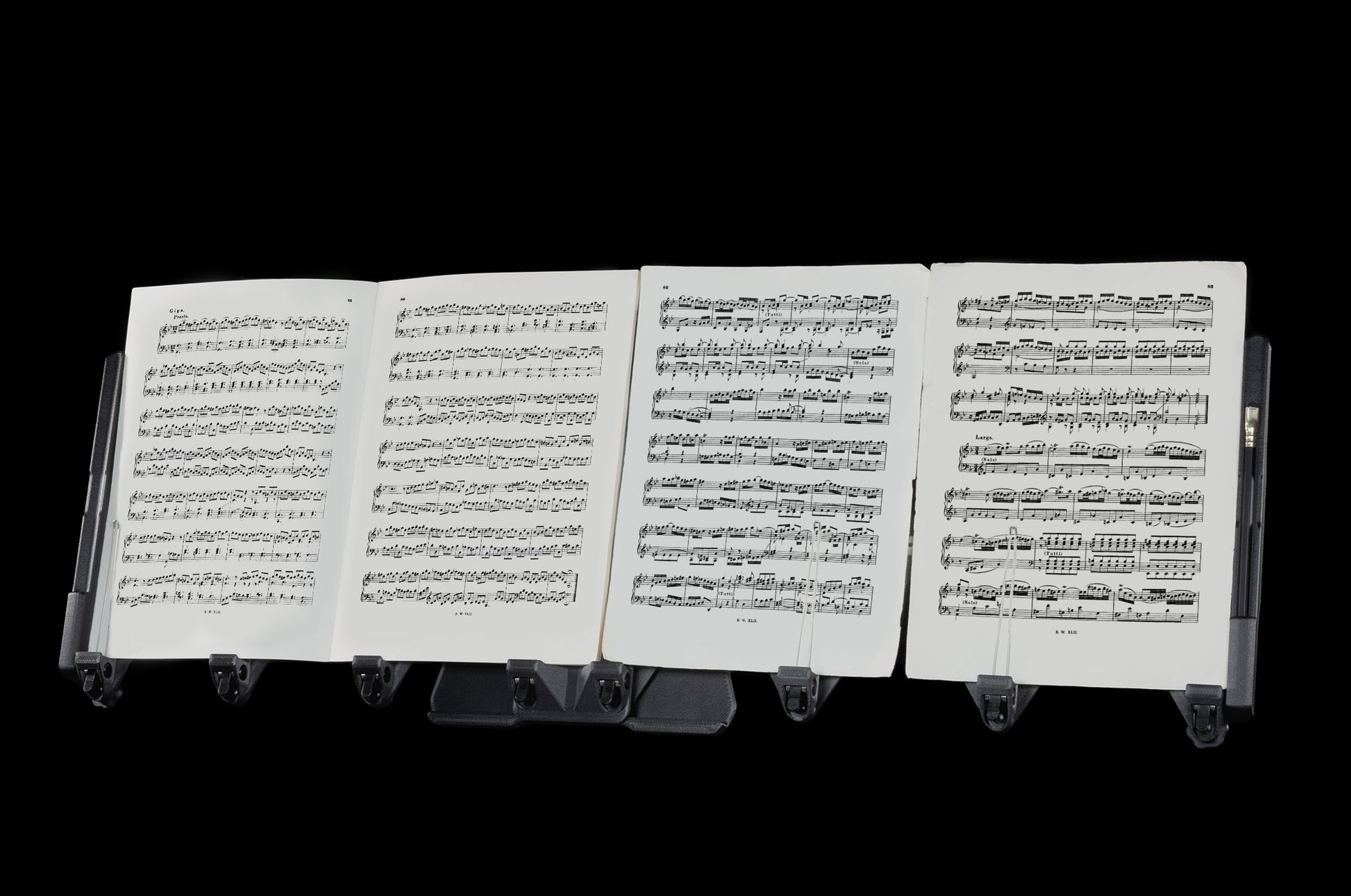 LONGA: A photo showing it extending with black background and holding one music book, two music sheets, and a pencil